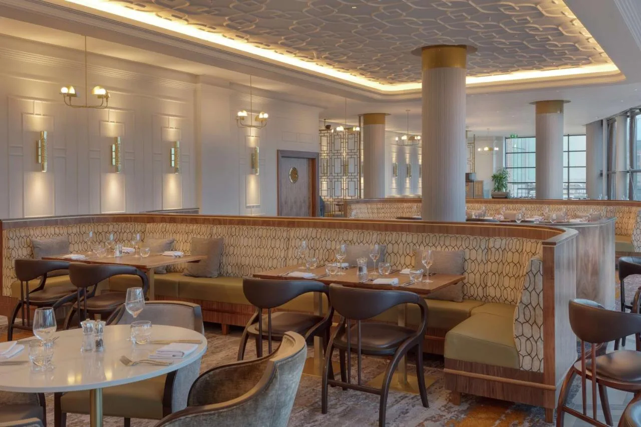 A restaurant with tables, chairs and a bar at Hilton Belfast in Belfast city centre