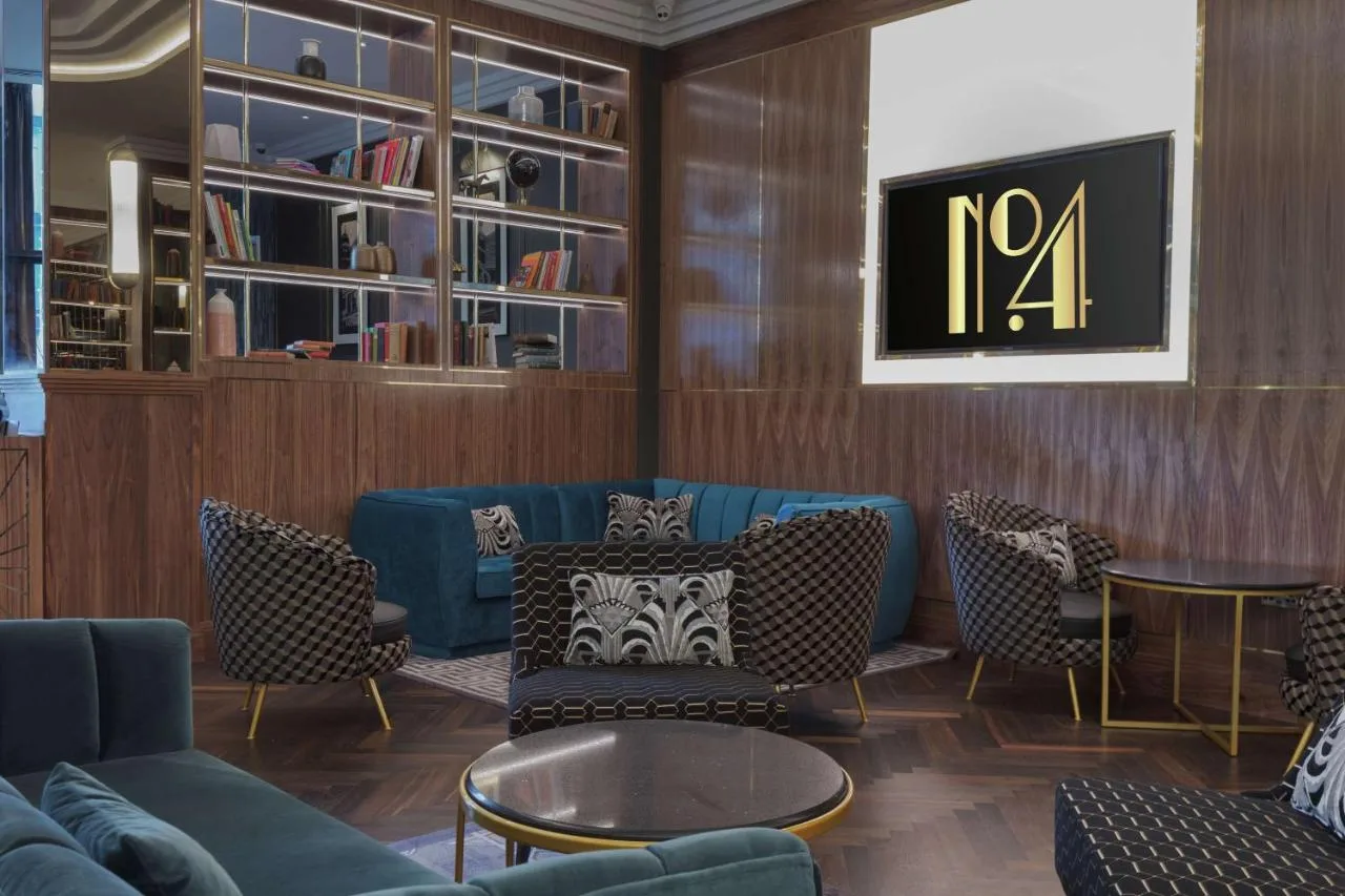 A living room-style lounge with a blue couch and chairs at Hilton Belfast