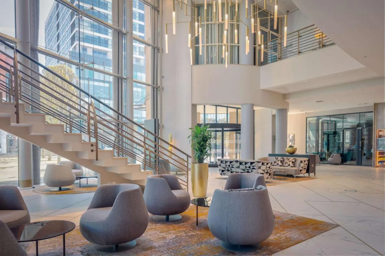 A lobby with a staircase and chairs at Hilton Belfast